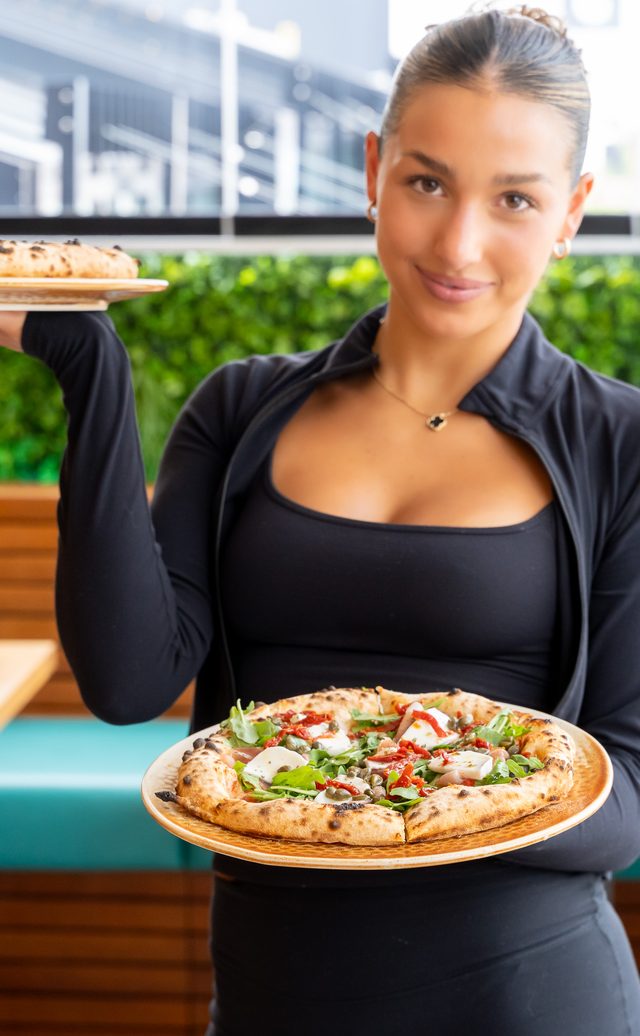 Server with a fresh brick-oven pizza at La Favella